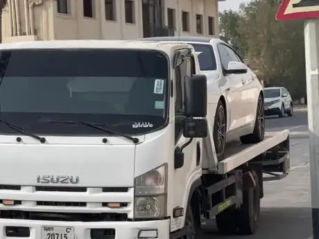 White flatbed truck with a pickup loaded on a city street — MZ Meer Car Recovery